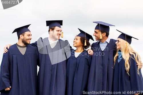 Image of happy students or bachelors in mortar boards