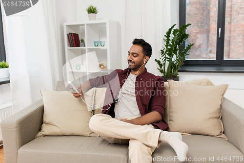 Image of man in earphones listening to music on smartphone