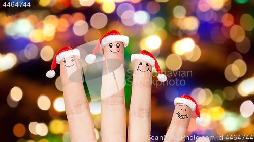 Image of close up of four fingers in santa hats over lights