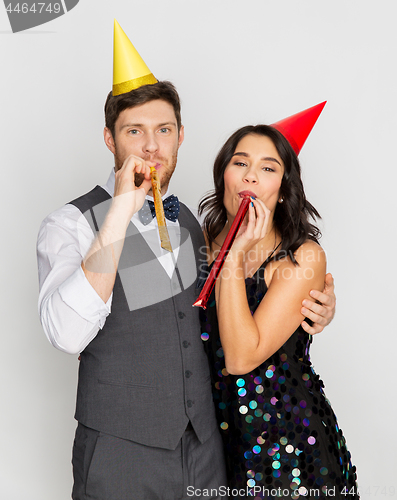 Image of happy couple with party blowers having fun