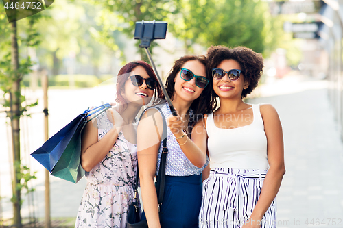 Image of women with shopping bags taking selfie outdoors