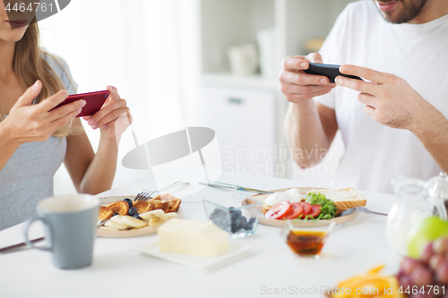 Image of close up of couple with smartphones at breakfast