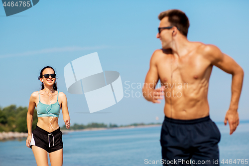 Image of couple with earphones running along on beach