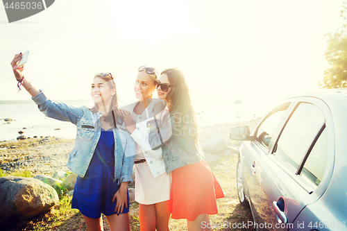 Image of happy women taking selfie near car at seaside