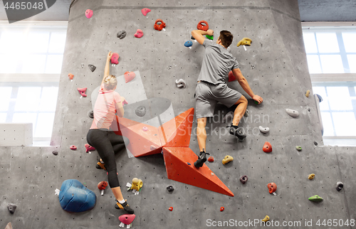 Image of man and woman climbing a wall at indoor gym