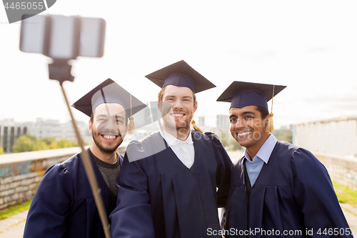 Image of happy male students taking picture by selfie stick