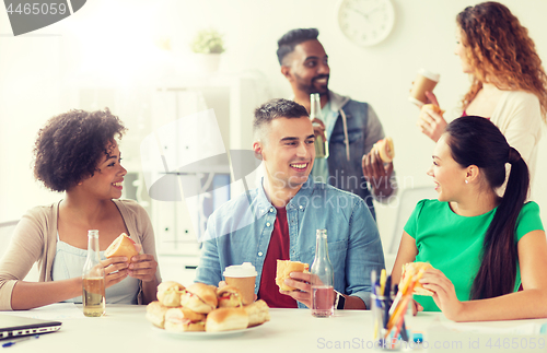 Image of happy friends or team eating at office party