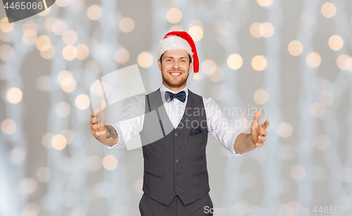 Image of happy man in santa hat holding something imaginary