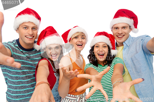 Image of happy friends in santa hats over white background