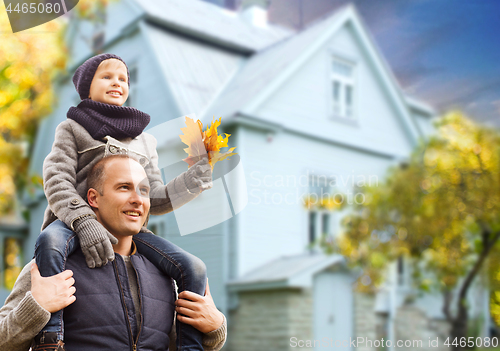 Image of father and son with autumn maple leaves over house