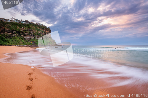 Image of Waves wash on the seashore washing away footprints