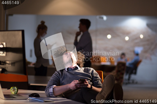 Image of businessman sitting with legs on desk at office