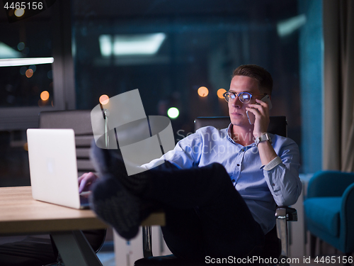 Image of businessman using mobile phone in dark office