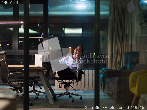 Image of businessman using mobile phone in dark office