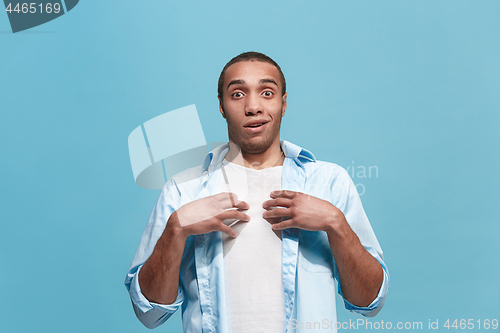 Image of The young attractive man looking suprised isolated on blue