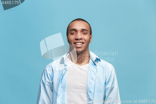 Image of The happy business man standing and smiling against blue background.