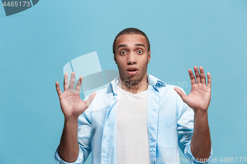 Image of The young attractive man looking suprised isolated on blue