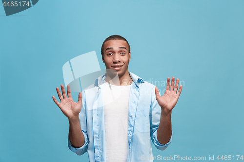 Image of The young attractive man looking suprised isolated on blue