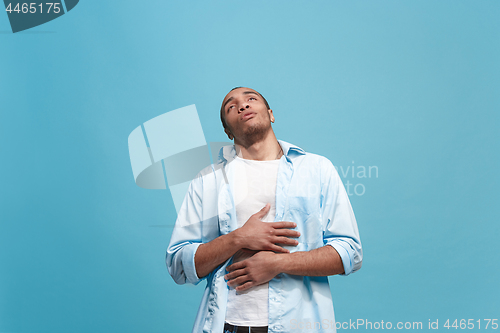 Image of The happy businessman standing and smiling against blue background.