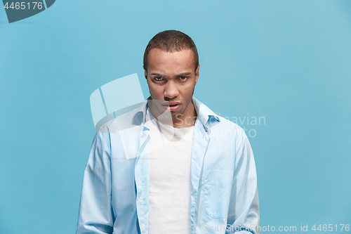 Image of The young emotional angry man on blue studio background