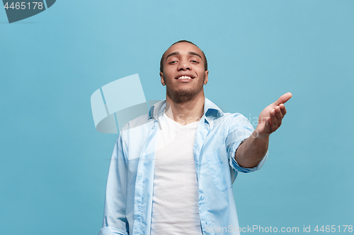 Image of The happy business man standing and smiling against blue background.