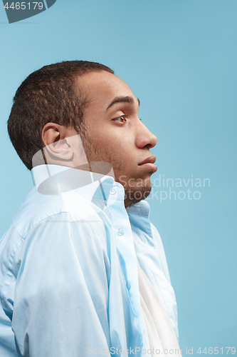 Image of Doubtful Afro-American man is looking frightenedly against blue background