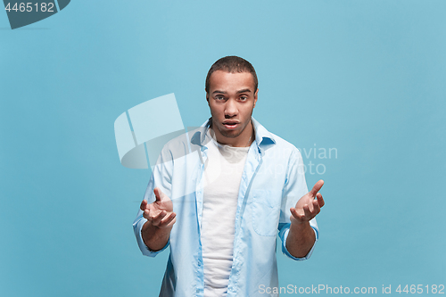 Image of Beautiful male half-length portrait isolated on blue studio backgroud. The young emotional surprised man