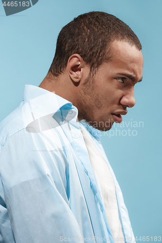 Image of The young emotional angry man on blue studio background