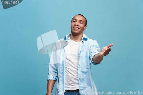Image of The happy business man standing and smiling against blue background.