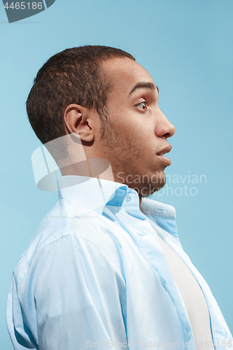 Image of Doubtful Afro-American man is looking frightenedly against blue background