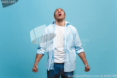 Image of The young emotional angry man screaming on blue studio background