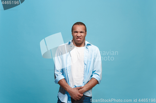 Image of Young man with disgusted expression repulsing something, isolated on the blue