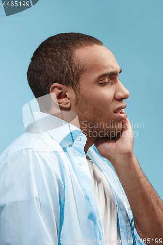 Image of Sad Afro-American man is having toothache. against blue background