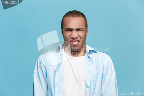 Image of Young man with disgusted expression repulsing something, isolated on the blue