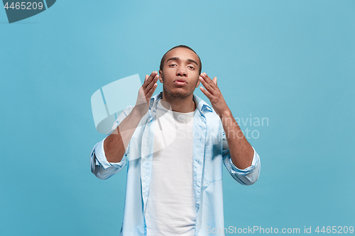 Image of Beautiful male half-length portrait isolated on blue studio backgroud. The young emotional surprised man