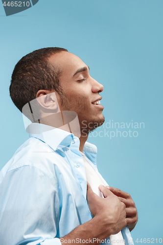 Image of The happy businessman standing and smiling against blue background.