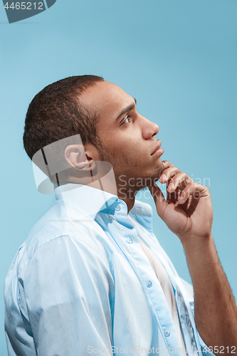 Image of Thoughtful Afro-American man is looking thoughtfully against blue background