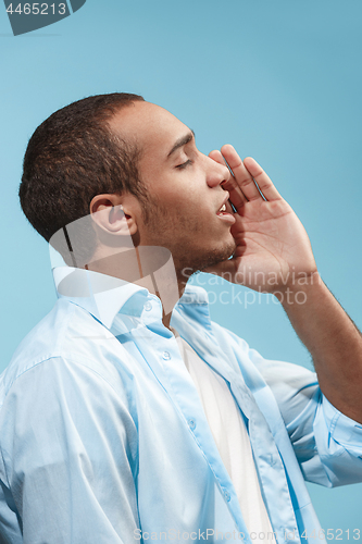 Image of Happy Afro-American man is shouting against blue background