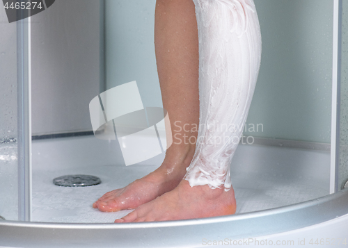 Image of Woman shaving legs at bathroom