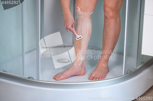 Image of Woman shaving legs at bathroom