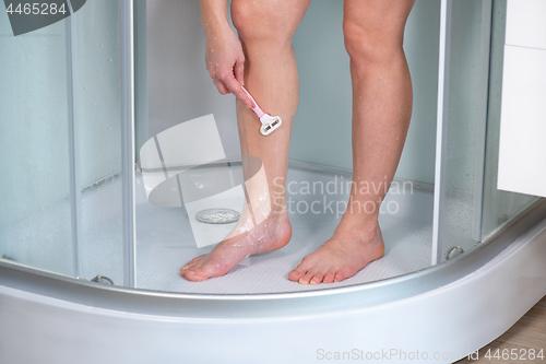 Image of Woman shaving legs at bathroom