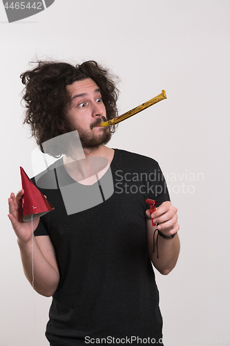 Image of Portrait of a man in party hat blowing in whistle