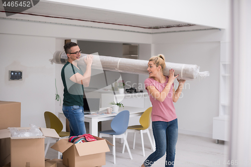 Image of couple carrying a carpet moving in to new home