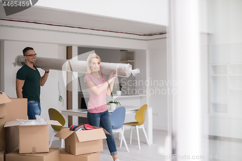 Image of couple carrying a carpet moving in to new home