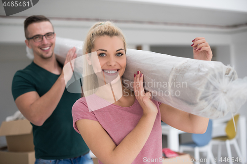 Image of couple carrying a carpet moving in to new home