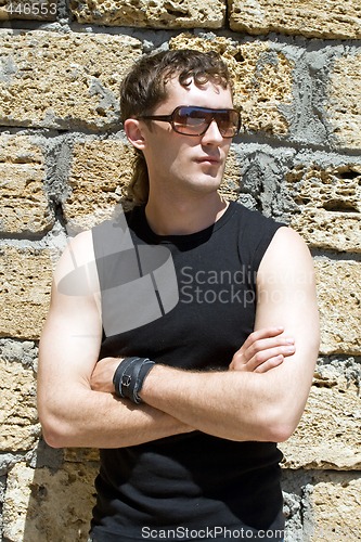 Image of Young man in sunglasses standing near a wall 2
