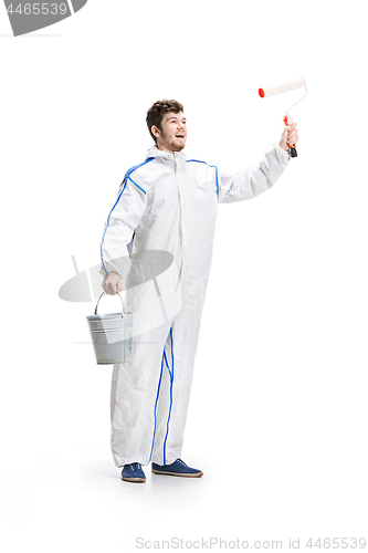 Image of Young male decorator painting with a paint roller climbed a ladder isolated on white background.