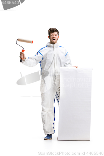 Image of Young male decorator painting with a paint roller climbed a ladder isolated on white background.