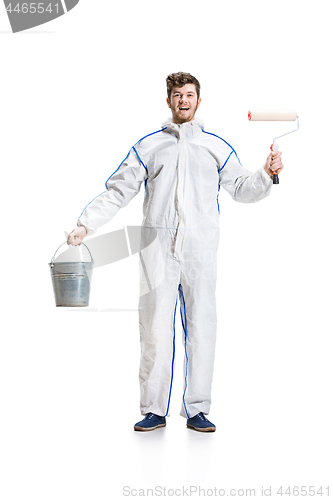 Image of Young male decorator painting with a paint roller climbed a ladder isolated on white background.