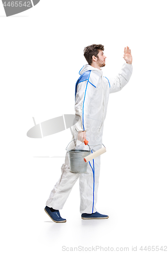 Image of Young male decorator painting with a paint roller climbed a ladder isolated on white background.